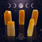 Five faceted orange-yellow crystal points or tumbled stone pieces arranged on a plain white surface.